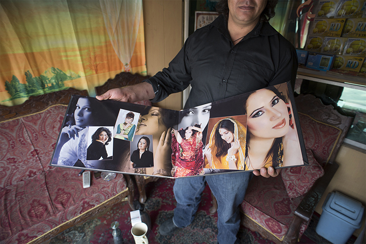 An Afghan wedding photographer shows bridal portraits at his photo studio in Kabul, March 6, 2014. Despite decades of conflict in Afghanistan, and several recent militant attacks, the country's capital Kabul is home to a vibrant youth scene of musicians, artists, athletes and activists. Shopping malls and cafes stand in the city, which is nonetheless beset by infrastructure problems and instability. Afghanistan is preparing for an election on April 5 that should mark the first democratic transfer of power in the country's history, but it has been hit by a tide of violence as the Islamist Taliban movement has ordered its fighters to disrupt the vote and threatened to kill anyone who participates.