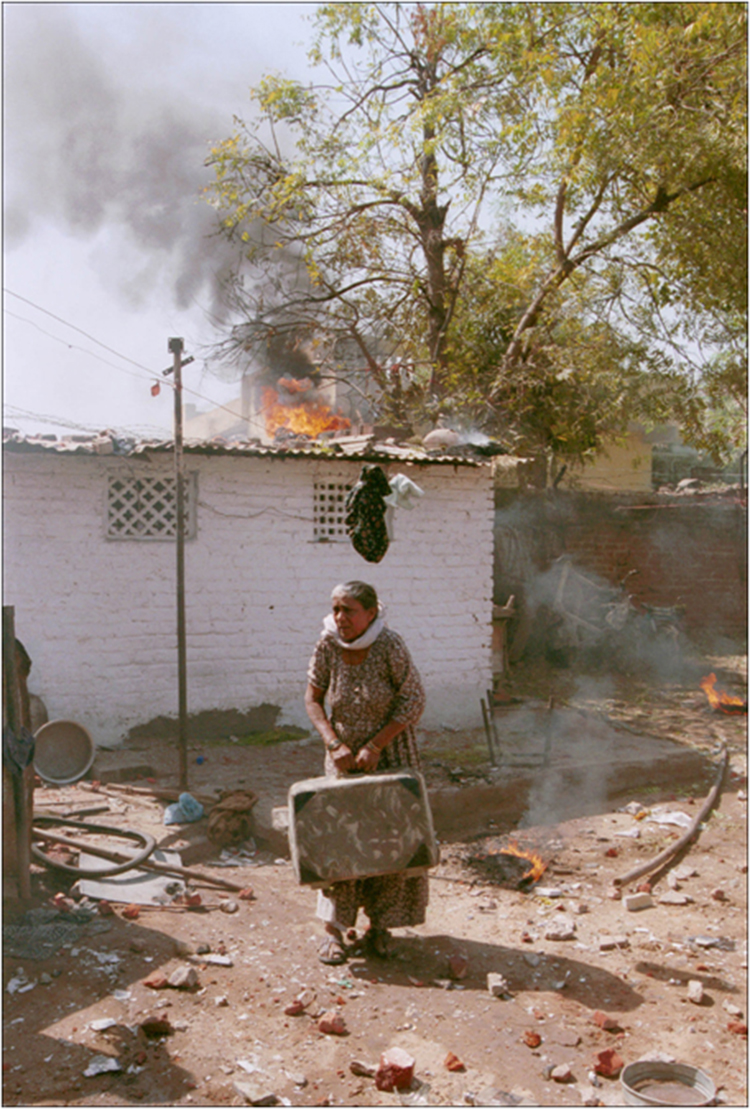 An old muslim woman tries to save her belongings at the Municipality Juna Quarters, a predominantly muslim area, after an angry Hindu mob set her house to fire in Ahmedabad, Gujrat. Clashes between the majority Hindus and minority Muslim communities have complete stopped normal life the city for the last few days.1/3/2002