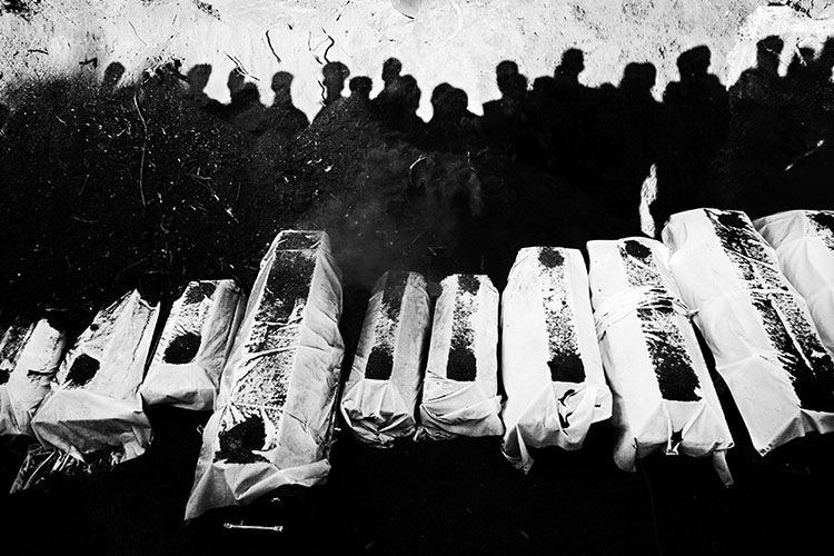 Q. Sakamaki The shadows of mourning relatives fall on a mass grave, the result of the June 15th bus attack which killed more than 64 people, many of them women and children. The Sri Lankan government accuses the LTTE rebels of the terror, but the Tamil political organization denies the claim. The situation in the country is at the brink of all-out war. Kabithigollewa, Sri Lanka. June 16, 2006.
